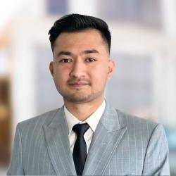 Man wearing light gray, pinstrip suit and black tie.