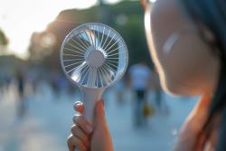 Female holding a white handheld fan