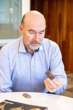 Professor Peter Ralph looking at a bioplastics 3D brick he is holding in his hand.