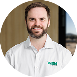 Man with short hair and a beard smiling and looking at the camera. He is wearing a WEM Civil business shirt. 