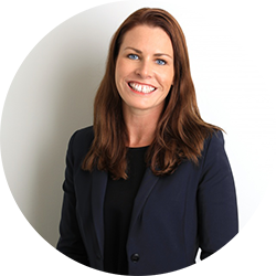 Woman with brown shoulder length hair in navy blue suit smiling and looking at the camera