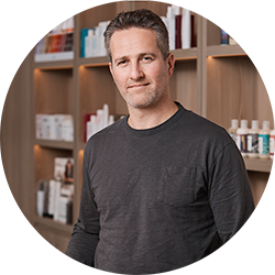 Man in a grey long sleeve tshirt smiling and looking at the camera