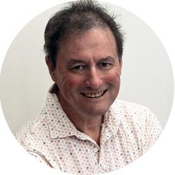 Man smiling and looking at the camera in a spotted buttoned shirt