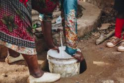 Woman from Uganda filling up a water bucket.