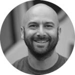 Black and white photo of a man with a beard smiling and looking at the camera