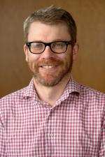 A chest up profile photo of Andrew Hurley smiling at the camera