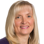 Head and shoulder shot of a woman with blonde shoulder length hair smiling and looking at the camera