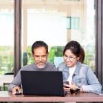 Younger woman with older man looking at computer