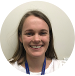 Charlotte Cahill smiling at camera. She has shoulder-length, light-brown hair. She wears a white top and a blue lanyard.