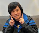 Chest up photo of Huu Hao Ngo with two fingers in the air either side of his face smiling at the camera