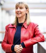 Waist up photo of Angela Dawson in a red jacket smiling off to the side of the camera