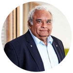 Prof Tom Calma AO smiling in an indoor portrait shot.