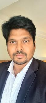 Close up chest up image of Biswajeet Pradhan in a white shirt and navy jacket looking at the camera