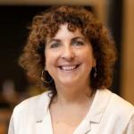 Jo Lampert smiles at the camera in a white top
